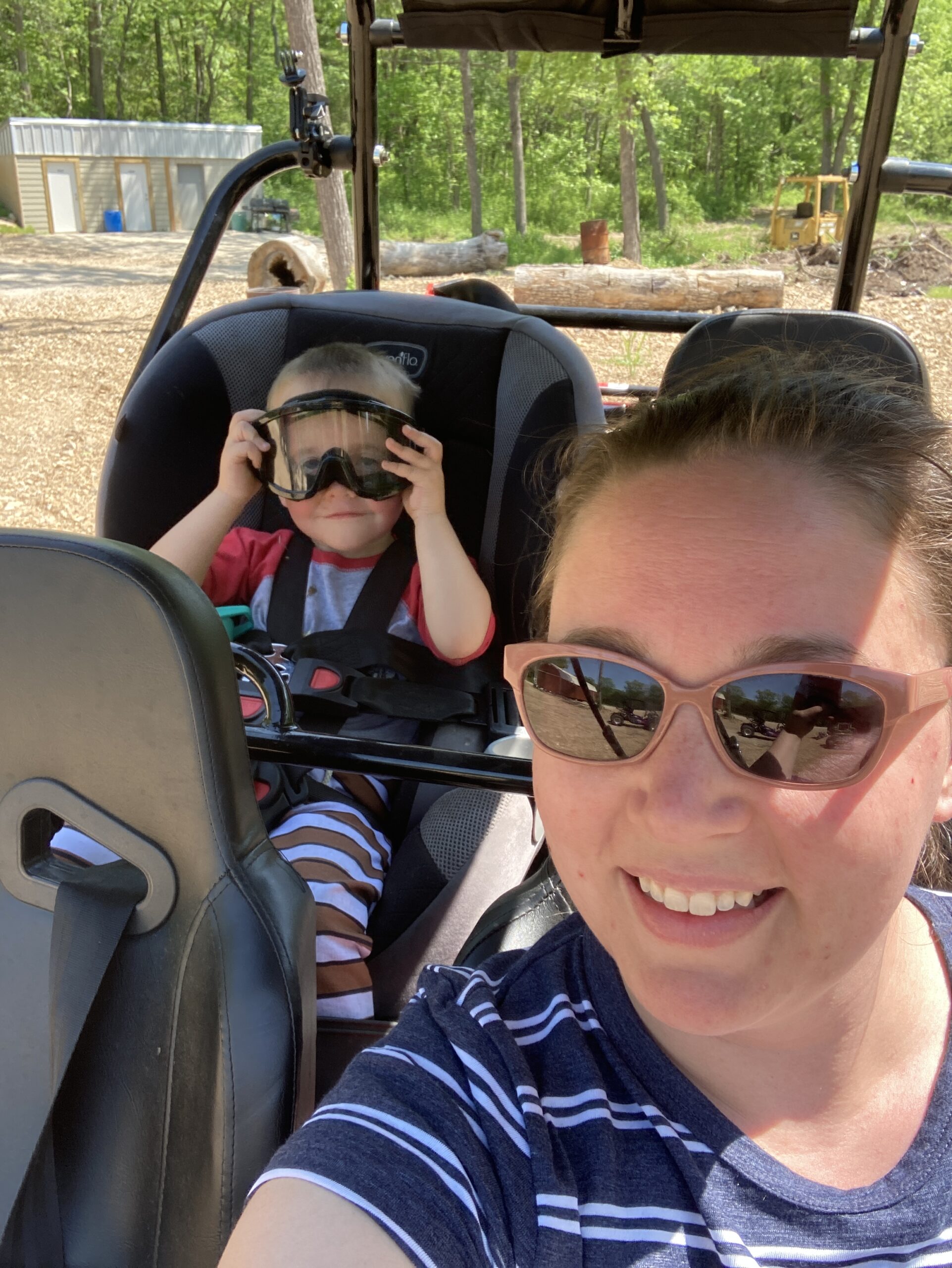 Toddler riding in a carseat installed in the back row of a 4 seater go kart